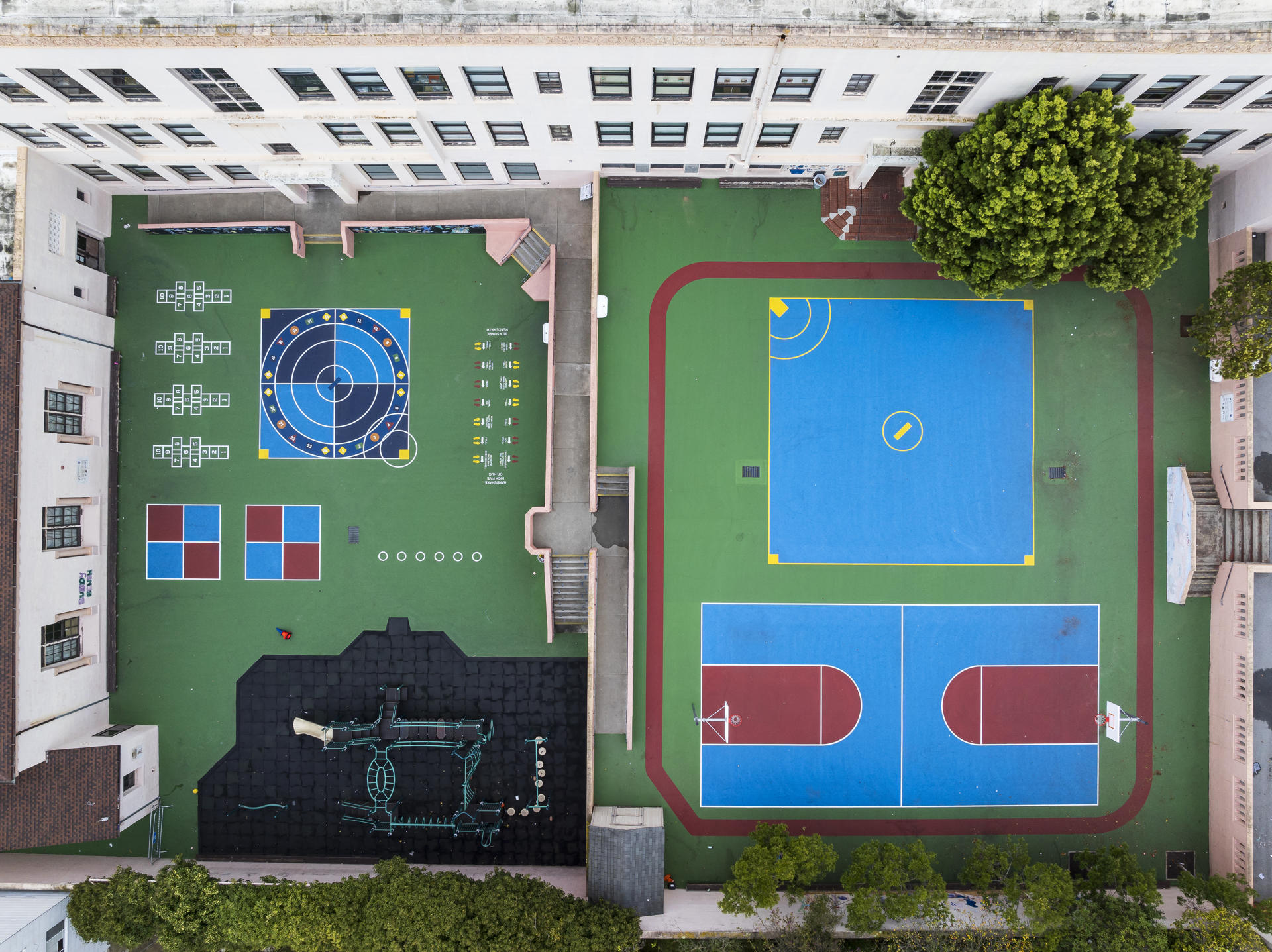 Aerial view of the playground at Sherman Elementary School in San Francisco. The playground has various multi-use and multi-color playground layouts done using Plexipave hardcourt acrylic resurfacer. Some of the layouts include a basketball court, hopscotch, foursquare and a general game court