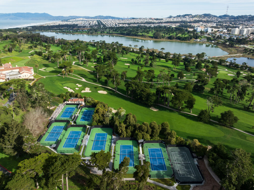 Aerial view of tennis courts and a golf course at Olympic Club in San Francisco. The tennis courts have been resurfaced using Har-Tru Proflex surfacing system in Championship Blue and Green coatings. One Har-tru green clay court is pictured.