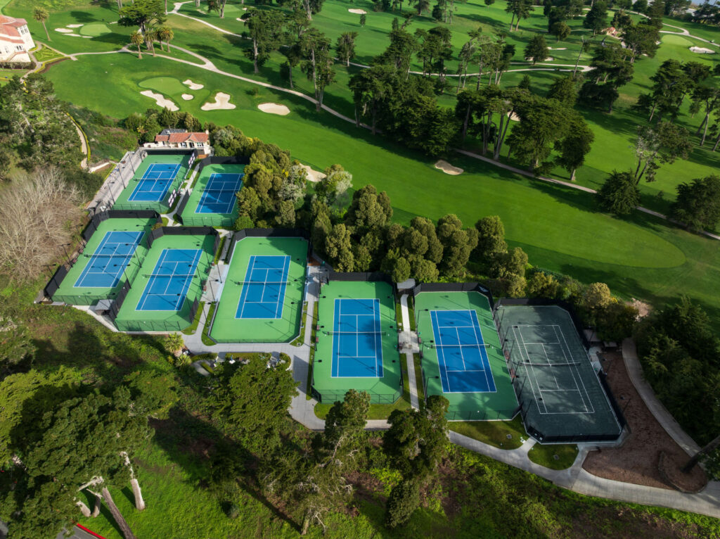 Aerial view of tennis courts and a golf course at Olympic Club in San Francisco. The tennis courts have been resurfaced using Har-Tru Proflex surfacing system in Championship Blue and Green coatings. One Har-tru green clay court is pictured.